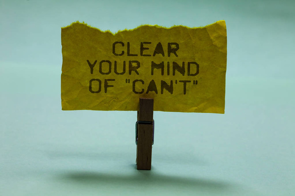Text sign showing Clear Your Mind Of Can t not. Conceptual photo Have a positive attitude thinking motivation Paperclip hold torn yellow page written brown words sky blue background. - Photo, Image