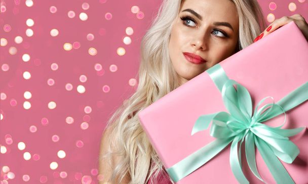 美しい女性がピンクとパステル グリーンのクリスマス プレゼント笑顔ピンクの新年のお祝いのギフト ボックスを保持します。  - 写真・画像