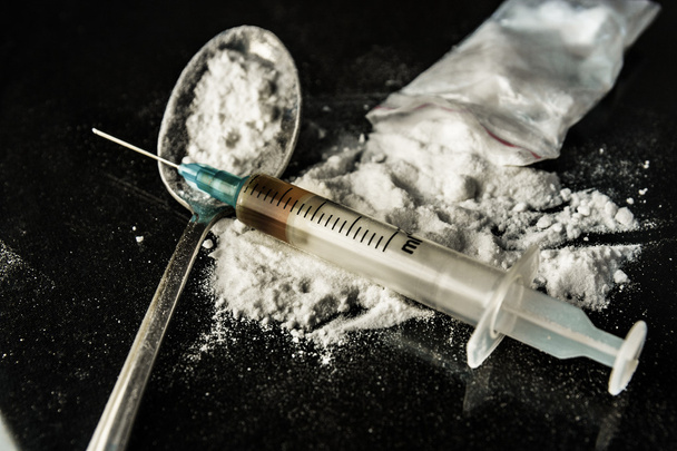 Drug syringe and cooked heroin on spoon - Foto, afbeelding