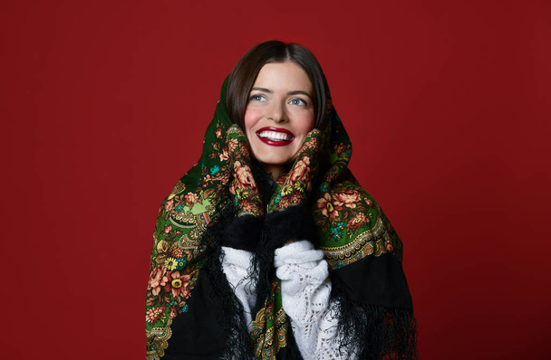 Portrait of High fashion glamour beautiful brunette hair Russian style woman in traditional scarf and gloves on red  - Fotó, kép