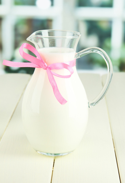 Pitcher of milk on table in room - Φωτογραφία, εικόνα