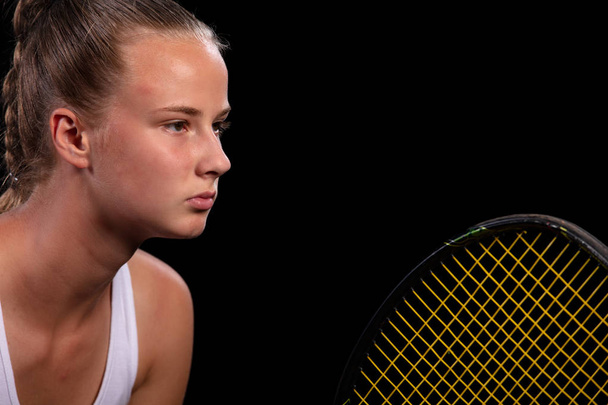 Portrait of beautiful woman playing tennis indoor. Isolated on black. - Фото, изображение