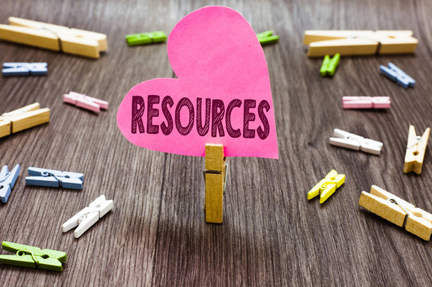 Writing note showing Resources. Business photo showcasing Money Materials Staff and other assets needed to run a company Clothespin holding pink paper heart several clothespins wooden floor. - Photo, Image