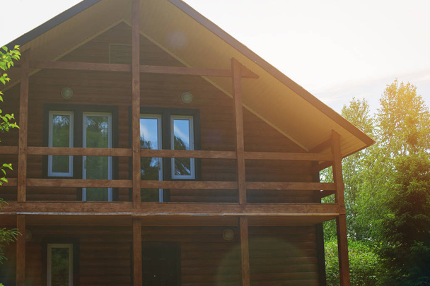 Casa de madera de troncos redondos con balcón y ventanas
. - Foto, Imagen