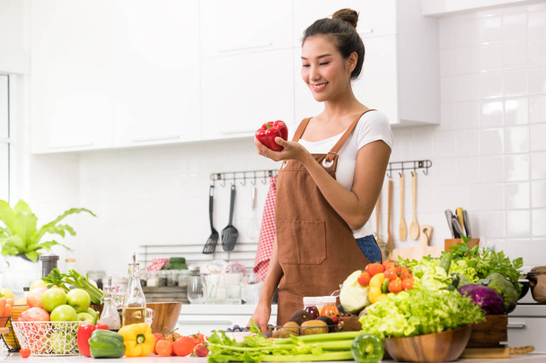 Aasian nainen keittiössä valmistamassa hedelmiä ja vihanneksia terveelliseen ateriaan ja salaattiin
 - Valokuva, kuva