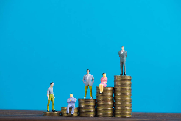 Figure miniature businessman or small people investor and office worker secretary standing on coin stack, for money and financial business success concept idea. - 写真・画像