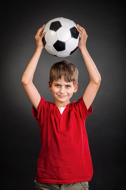 Cute boy is holding a football ball. Soccer ball - Фото, изображение