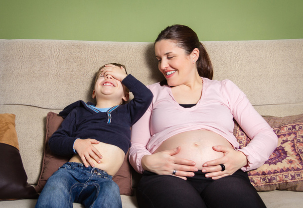 Schwangere Mutter und Sohn lachen und vergleichen Bäuche - Foto, Bild