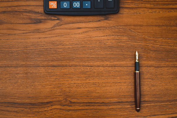 Stilografica o penna inchiostro con calcolatrice su tavolo da lavoro in legno con spazio copia, idea di concetto scrivania ufficio
. - Foto, immagini