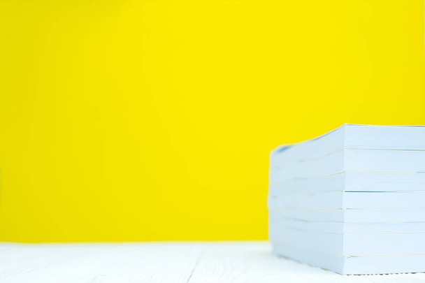 Pile of book on white table with yellow wall background. - Foto, afbeelding