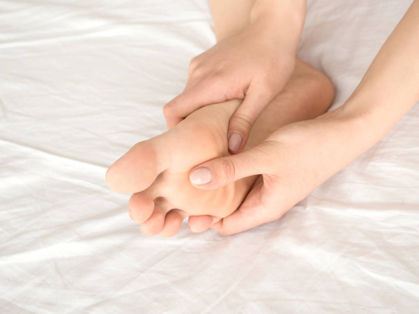 woman massaging her tired feet on the bed. close up view - Photo, Image