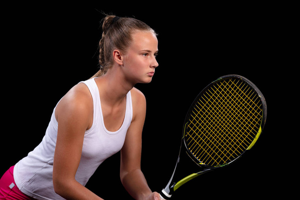 Portrait of beautiful woman playing tennis indoor. Isolated on black. - Photo, image