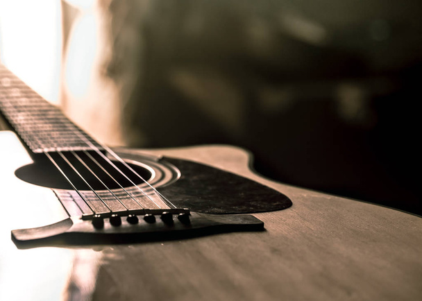 Akoestische gitaar close-up op een prachtige gekleurde achtergrond, het concept van snaarinstrumenten - Foto, afbeelding