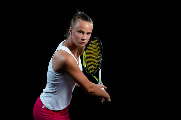 Portrait of beautiful woman playing tennis indoor. Isolated on black. - Foto, afbeelding