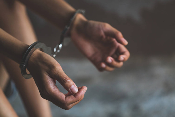 Close-up van handen in handboei, vrouwelijke gevangene, Arrested vrouw geboeid handen. Gevangene of gearresteerd terrorist, hacker, bribetaker.  - Foto, afbeelding