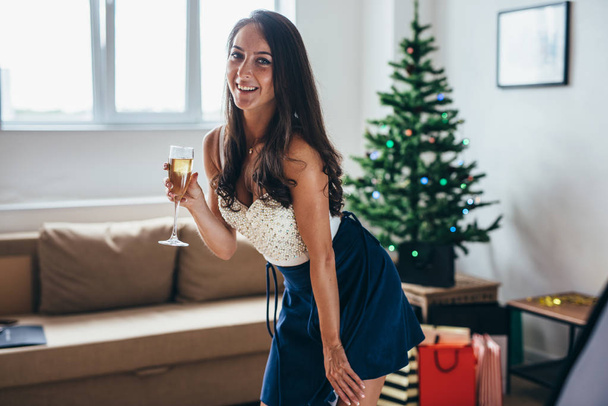 Christmas, New Year. Happy young woman with glass of champagne at home - 写真・画像