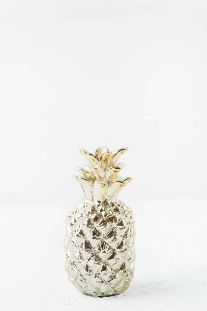 Gold pineapple decoration object on light background with copy space, vertical shot - Foto, imagen