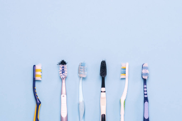 Several different used toothbrushes on a blue background. Toothbrush change concept, oral hygiene, big and friendly family. Flat lay, top view - Photo, Image