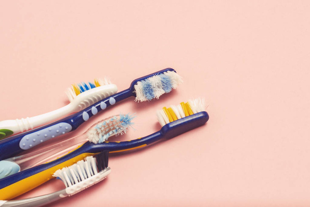 Several different used toothbrushes on a pink background. Toothbrush change concept, oral hygiene, big and friendly family, toothbrush selection. Flat lay, top view - Photo, Image