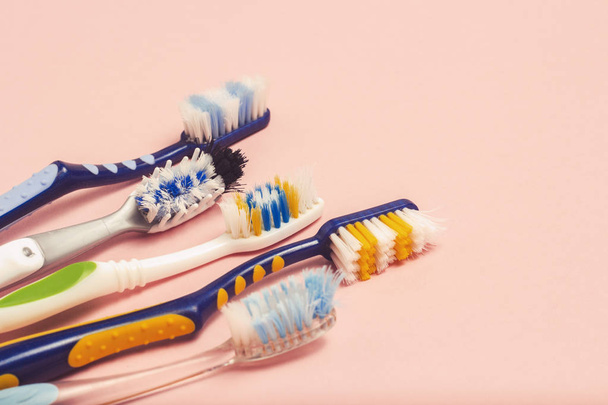 Несколько различных используемых зубных щеток на розовом фоне. Концепция смены зубной щетки, гигиена полости рта, большая и дружелюбная семья, выбор зубной щетки. Плоский, вид сверху
 - Фото, изображение