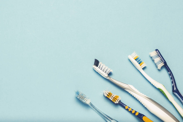 Several different used toothbrushes on a blue background. Toothbrush change concept, oral hygiene, big and friendly family. Flat lay, top view - Foto, Imagen