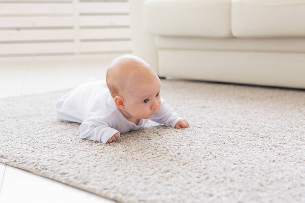 Childhood, babyhood and people concept - little baby boy or girl crawling on floor at home - Photo, Image