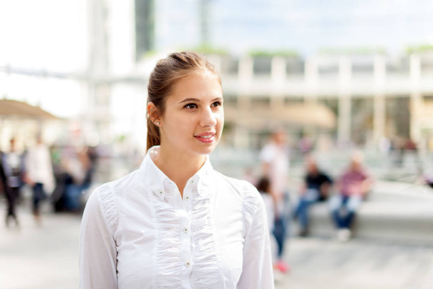 Beautiful young woman walking in a crowded square - Fotoğraf, Görsel