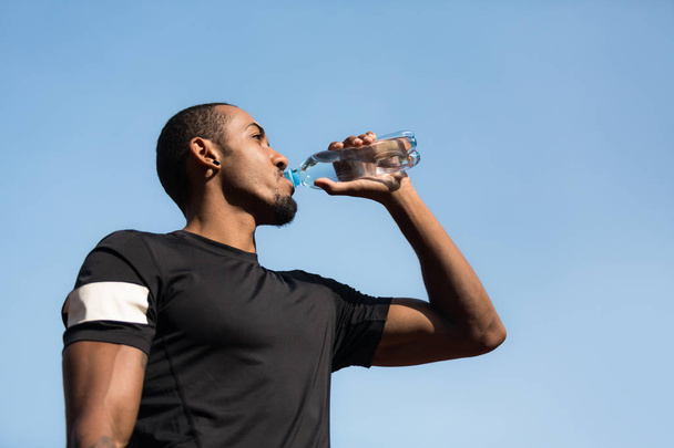 Mann ruht sich aus und trinkt Wasser nach dem Laufen - Foto, Bild