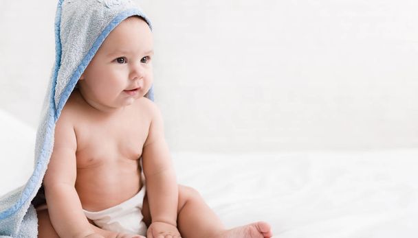 Schattige kleine babyjongen in hooded handdoek na bad - Foto, afbeelding