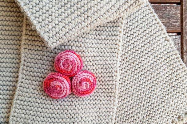 Bufanda de tejido de punto beige con adorno rojo en bolas rojas / flores de rosas, fondos de textura
 - Foto, imagen