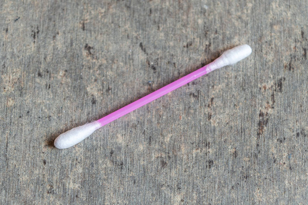 A cotton swab used for cleaning ears kept on a textured grey table - Photo, Image