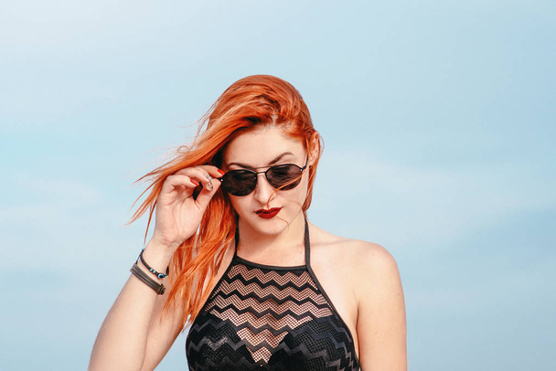 portrait of stylish adorable redhead white lady in sunglasses in desert - Photo, Image