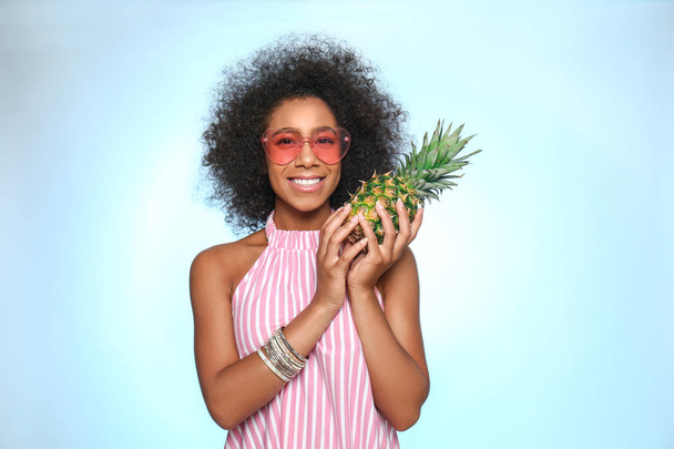 Beautiful African-American woman with pineapple on color background - 写真・画像