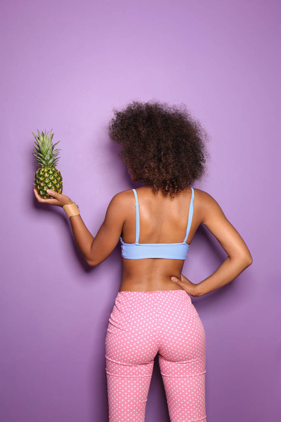 Schöne afroamerikanische Frau mit Ananas auf farbigem Hintergrund - Foto, Bild