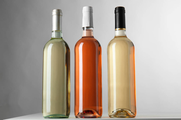 Flaschen mit verschiedenen Weinsorten auf grauem Hintergrund - Foto, Bild