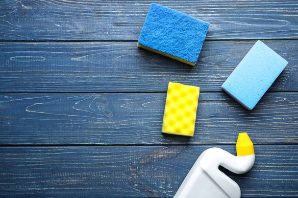 Detergent with cleaning sponges on color wooden background - Photo, Image
