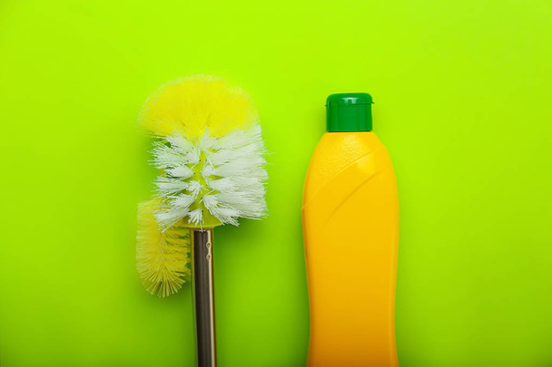 Bottle of detergent with toilet brush on color background - 写真・画像