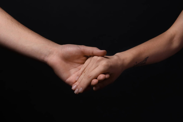 Man and woman holding hands on dark background - Photo, Image