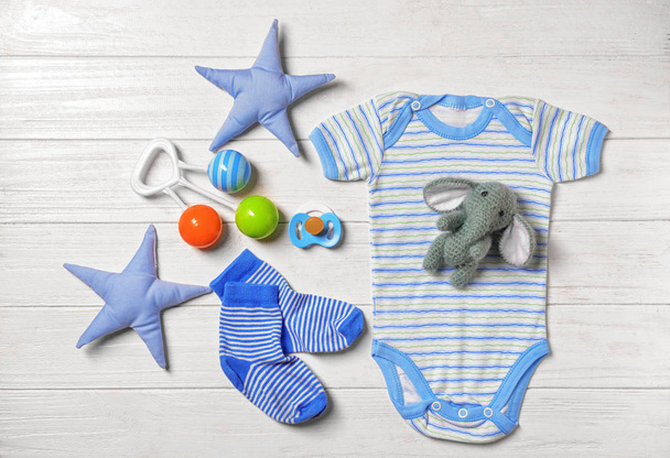 Ensemble de vêtements et accessoires pour bébés sur fond blanc en bois, pose plate
 - Photo, image