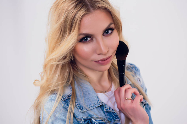 Beauty Woman with Makeup Brushes. Natural Make-up for Blonde Model Girl with Blue Eyes. Beautiful Face. Makeover. Perfect Skin. Applying Holiday Makeup with orange color lipstick and manicure. - Fotoğraf, Görsel