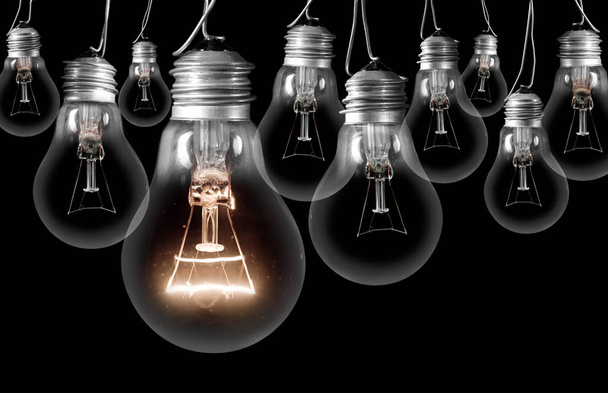Foto de lâmpadas escuras e brilhantes; conceito de ideia, inovação, singularidade e destaque; isolado em fundo preto
 - Foto, Imagem
