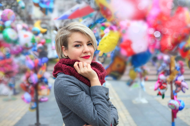 Closeup of a beautiful fashionable young woman. A walk in the autumn city, shot on the background of festive balloons. - Photo, Image