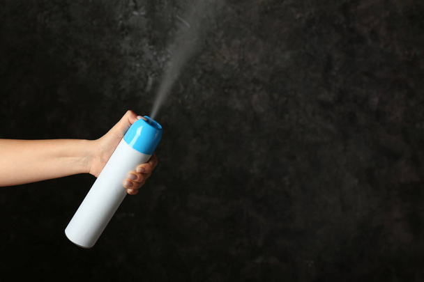 Donna che spruzza deodorante per ambienti su sfondo scuro
 - Foto, immagini
