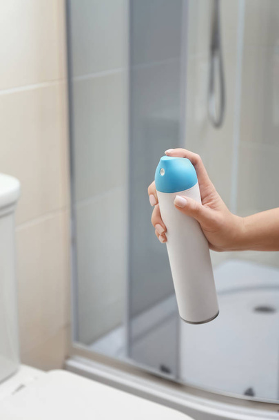 Mulher segurando spray ambientador no banheiro
 - Foto, Imagem