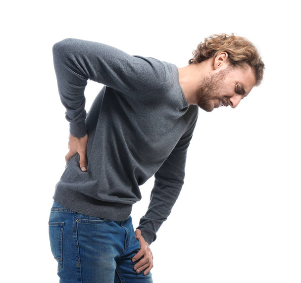 Young man suffering from back pain on white background - Фото, изображение