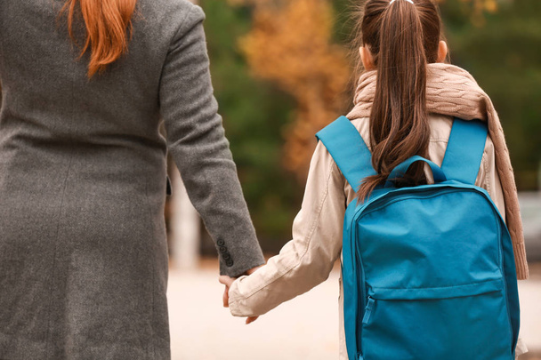 Χαριτωμένο κορίτσι πηγαίνει στο σχολείο με τη μητέρα του σε εξωτερικούς χώρους - Φωτογραφία, εικόνα