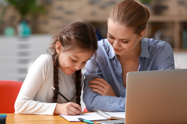 Cute girl with mother doing homework at home - Фото, зображення