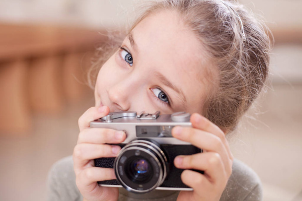 Κορίτσι με ένα ρετρό κάμερα κάνει μια φωτογραφία, studio που γυρίστηκε. - Φωτογραφία, εικόνα