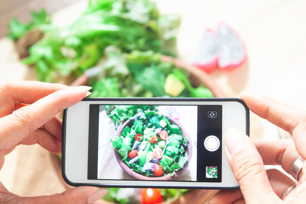 Nő kezébe véve fotó saláta tál-val mozgatható telefon - Fotó, kép