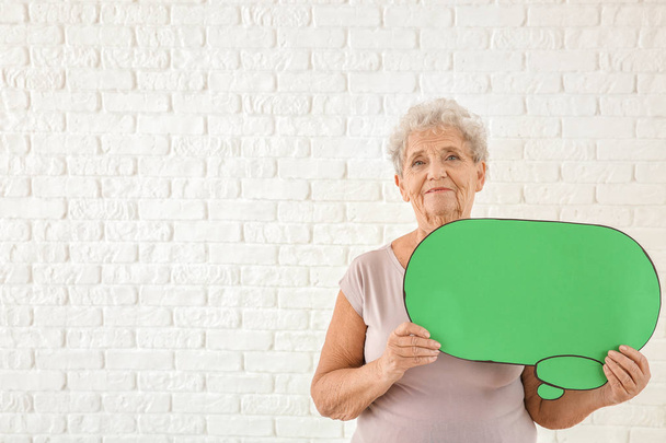 Senior woman with blank speech bubble on white background - Foto, afbeelding